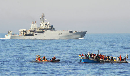 Ein überfülltes Flüchtlingsboot und zwei Schlauchboote der Bunde...