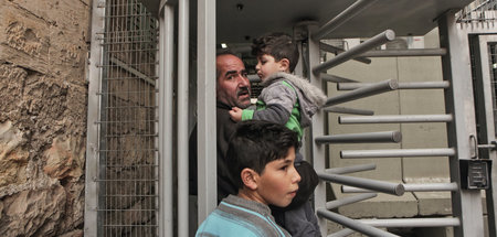 Ein palästinensischer Vater passiert mit seinen Kindern einen Ch...