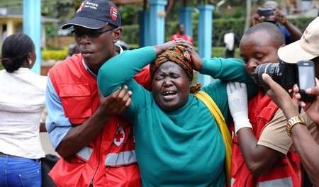 Mitarbeiter des Roten Kreuzes eskortieren eine Frau, die einen F...