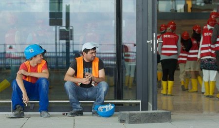 Pause am BER: Bauarbeiter (l.) und Besuchergruppe am neuen Haupt...