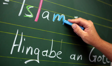 Ein Religionslehrer schreibt an die Tafel, hier allerdings in ei...