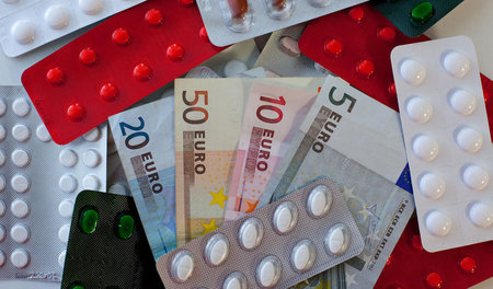 Tabletten und Euro-Scheine liegen auf einem Tisch einer Apotheke
