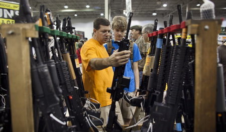 Besucher einer Waffenmesse in den USA begutachten das neueste Mo...