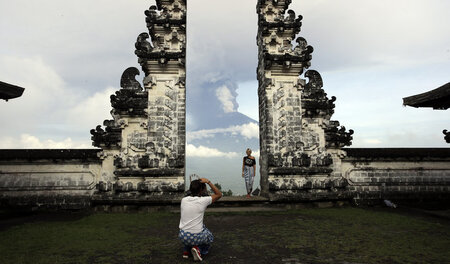 Touristen auf Bali am Montag. Im Hintergrund spuckt der Vulkan G... Touristen auf Bali am Montag. Im Hintergrund spuckt der Vulkan G...