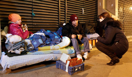 Eine Helferin versorgt Obdachlose in Paris mit heißen Getränken,... Eine Helferin versorgt Obdachlose in Paris mit heißen Getränken,...