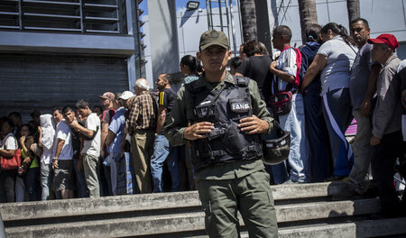 Ein Polizist bewacht am Samstag in Caracas einen Lebensmittellad...