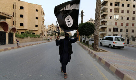 Ein Dschihadist der Miliz »Islamischer Staat« (IS) mit Flagge in... Ein Dschihadist der Miliz »Islamischer Staat« (IS) mit Flagge in...