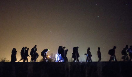 Flüchtlinge gehen nachts über Bahnschienen auf einen Checkpoint ...