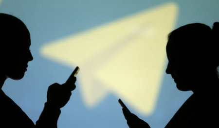 Beliebter Messengerdienst: Handynutzer vor dem Telegram-Logo Beliebter Messengerdienst: Handynutzer vor dem Telegram-Logo