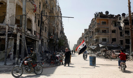 Eine syrische Fahne weht in einer stark zerstörten Straße in Dum... Eine syrische Fahne weht in einer stark zerstörten Straße in Dum...