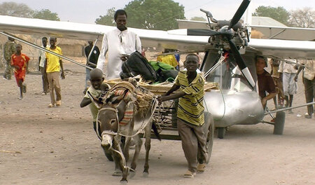 Nach seiner Landung in Kodok im Südsudan helfen die Einheimische...