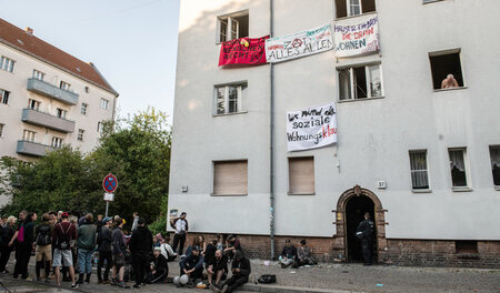 »Wohnen ist Menschenrecht«: Demonstranten stehen vor einem beset...