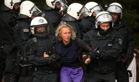 Gefahrengebiet Wald: Polizeibeamte führen eine Aktivistin ab (Mo...