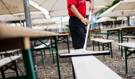 Arm trotz Arbeit: Ein Kellner reinigt Bierbänke in Baden-Württem...