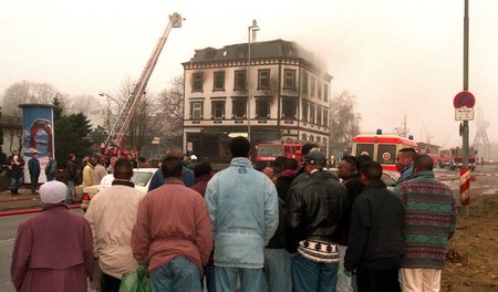 Asylbewerber blicken auf das ausgebrannte Haus in der Lübecker H...