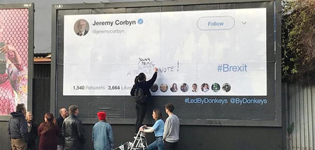 Passanten fordern in London auf einer Plakatwand von Jeremy Corb...