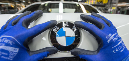 Ein Mitarbeiter montiert das BMW-Emblem auf den Kofferraumdeckel...