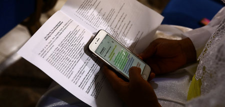 »Schon jetzt banal« (Prüfblick auf Smartphone mit Bibel-Passage) »Schon jetzt banal« (Prüfblick auf Smartphone mit Bibel-Passage)