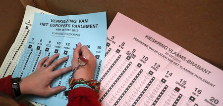 Eine Wählerin am Sonntag in Belgien mit Unterlagen für Parlament...