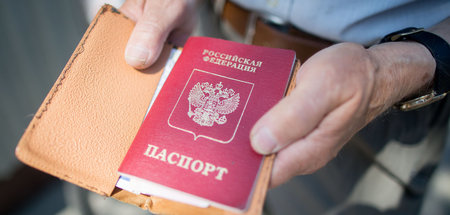 Ein Mann hält einen russischen Pass in den Händen
