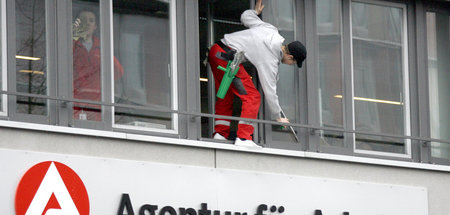 Fensterputzer reinigt die Fassade einer Dienststelle der Agentur...