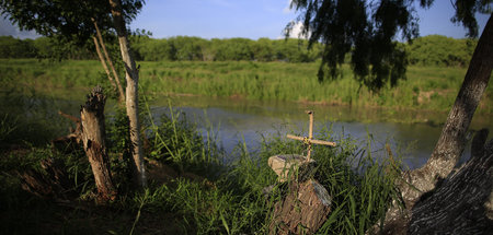 Ein Kreuz auf einem handgemachten Denkmal am Ufer des Grenzfluss