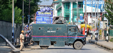 Ein Polizist neben einem gepanzerten Fahrzeug im indischen Teil 