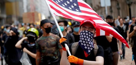 Prowestlicher Demonstrant in Hongkong mit US-Flagge und »MAGA-Hu...