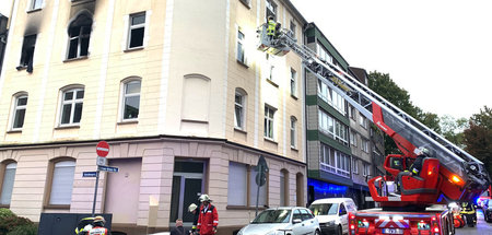 Einsatzkräfte der Feuerwehr vor dem Haus, in dem in einer Wohnun