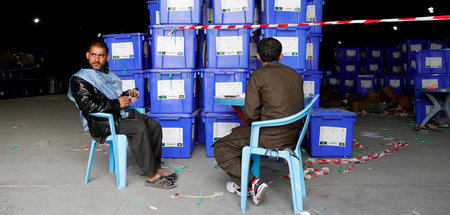 Mitarbeiter der afghanischen Wahlkommission sitzen neben Kisten ...
