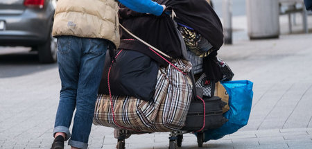 Eine obdachlose Frau schiebt einen Wagen mit ihren Habseligkeite...