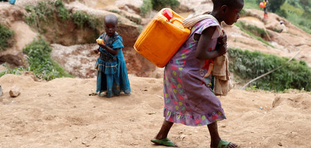 Mädchen trägt Wasserbehälter in Coltan-Mine in Kamatare in der D... Mädchen trägt Wasserbehälter in Coltan-Mine in Kamatare in der D...