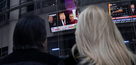 Menschen auf dem Times Square in New York verfolgen am Mittwoch ...