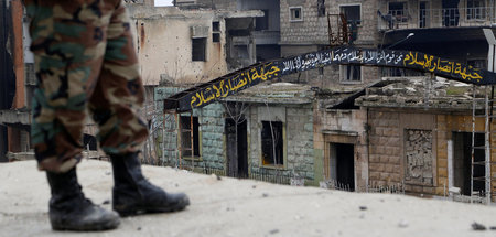 Ein Soldat der syrischen Armee steht auf einem Dach in der Stadt...