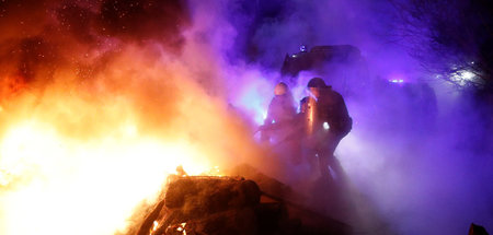 Ukrainische Feuerwehrmänner löschen eine brennende Straßenblocka...