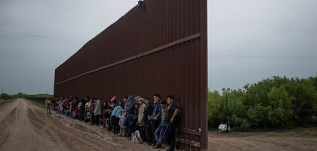 Geflüchtete aus Lateinamerika warten an der Grenzmauer zwischen 