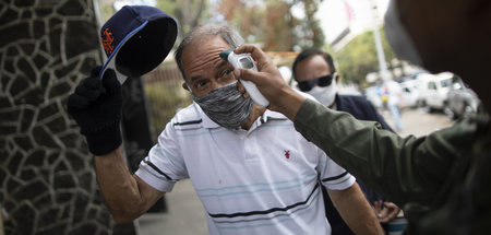 Ein Soldat misst vor einem Supermarkt in Caracas die Temperatur ...