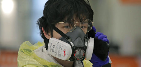 Passagier am Flughafen Hongkong mit Schutzanzug und Gesichtsmask