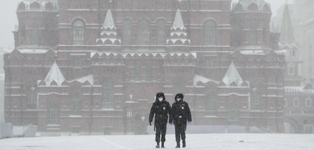 Polizeibeamte mit Schutzmasken auf dem leeren, schneebedeckten R...