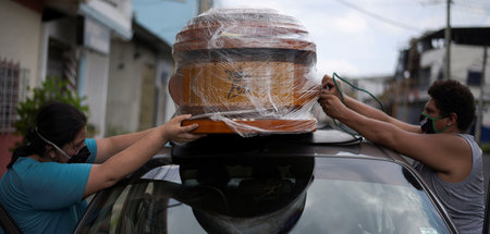 Zwei Personen machen einen Sarg auf dem Dach eines Autos in Guay...