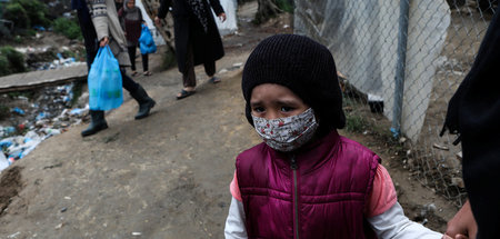 Ein Mädchen mit Atemschutzmaske in der Nähe des Flüchtlingslager...