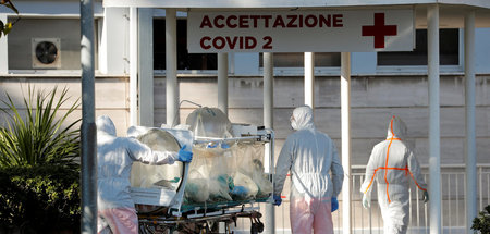 Medizinisches Fachpersonal in Schutzkleidung vor einem Krankenha...