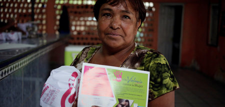 Eine Frau mit einem Werbeplakat für die Regierungskampagne »Das ...