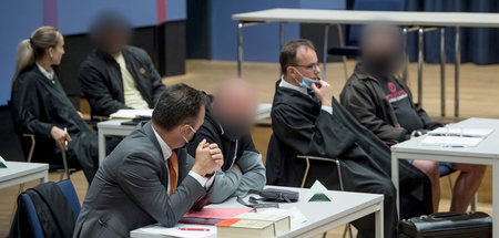 Drei der sechs als Mitläufer angeklagten Männern im Saal der Mus...