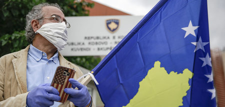 Mann mit Kosovo-Fahne und Handy vor dem Parlament in Pristina (3...