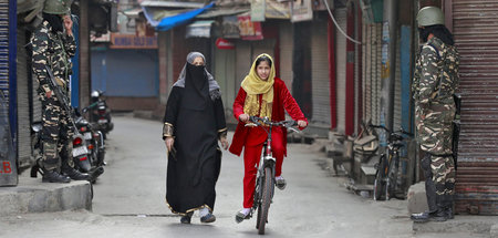 Ein Mädchen fährt auf ihrem Fahrrad durch die kaschmirische Stad...