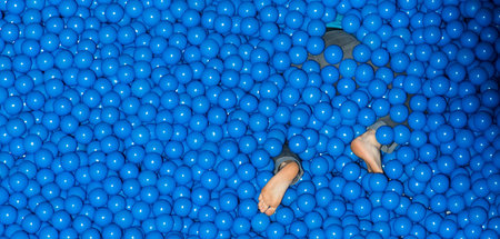 Messebesucher in einem blauen Bällebad am Stand von IBM bei der