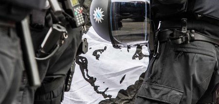 Polizisten stehen bei einer Kundgebung vor einer Darstellung von...