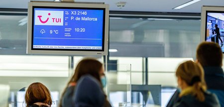 Reisende warten in einer Schlange am Check-in für einen der erst...