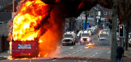 Polizeifahrzeuge hinter einem brennenden Bus am Mittwoch in Belf...